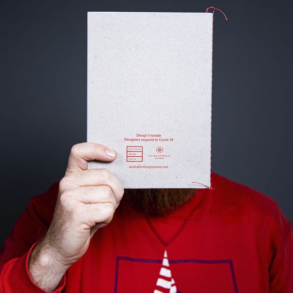 Man with red shirt holding a book in front of face